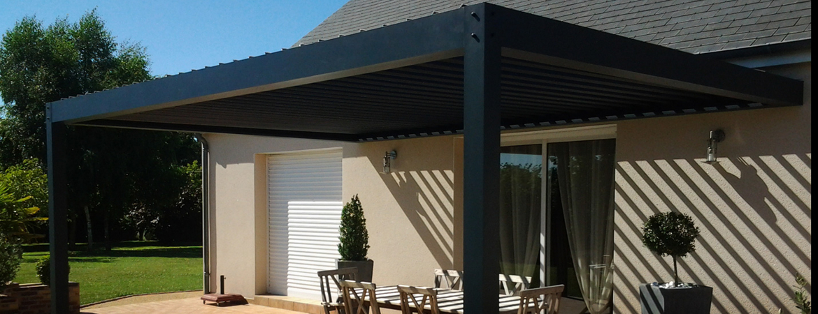 Pergola bioclimatique avec lames orientables, installée contre une maison